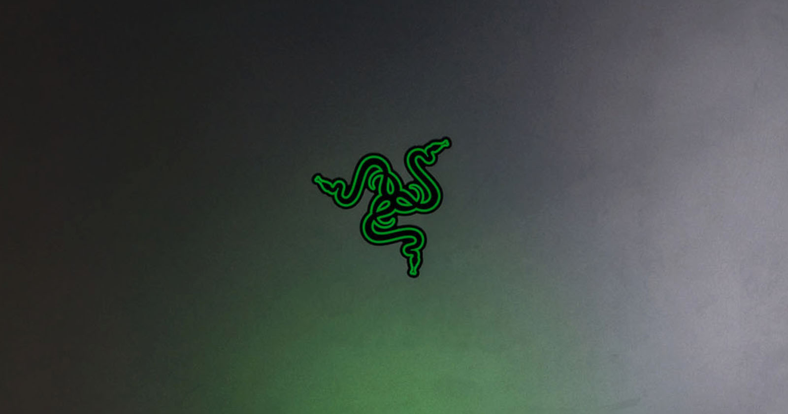 A gray surface features a bright green logo of three intertwined snakes forming a symmetrical design, commonly associated with the Razer brand. The overall appearance is sleek and modern.