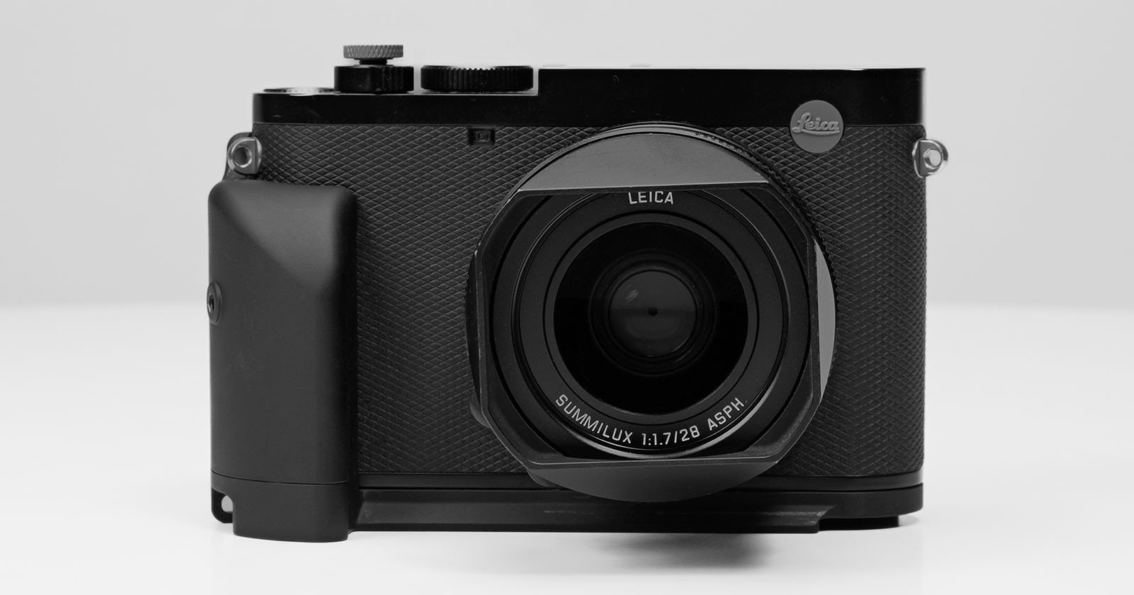 A sleek, black Leica camera is shown facing forward against a plain background. The Leica logo is visible on the upper right of the body, and the lens prominently displays text reading SUMMILUX 1:1.7/28 ASPH. The camera has textured grips and multiple dials.