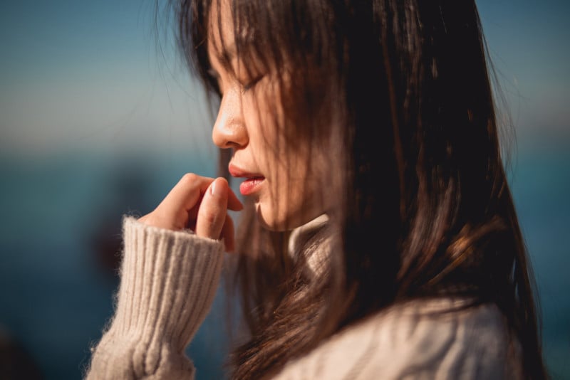 A portrait of a woman with her eyes closed and hand up to her face