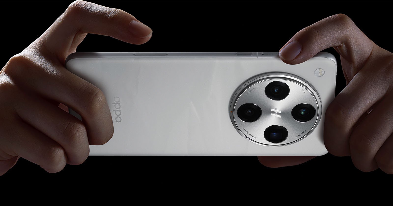 Close-up of a person holding a white Oppo smartphone horizontally with both hands against a black background. The phone features a prominent circular camera module with multiple lenses.