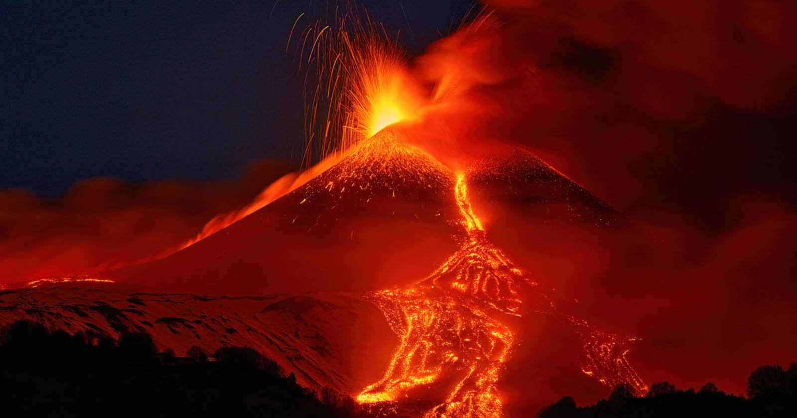 A volcano erupting at night, spewing bright orange lava and ash into the dark sky, with molten lava flowing down its slopes and smoke billowing around the eruption.