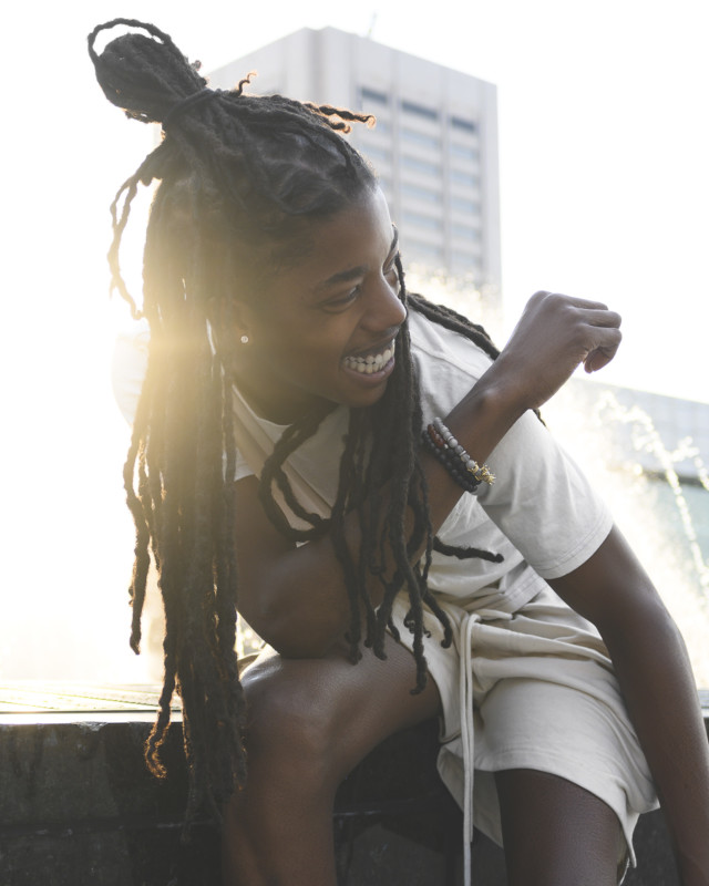 A portrait of a person laughing with the sun behind their hair