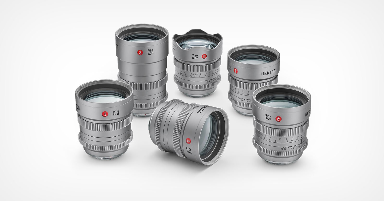 Five silver Leica camera lenses are arranged on a white background, with four standing upright and one lying on its side. The lenses feature engraved markings and red Leica logos.