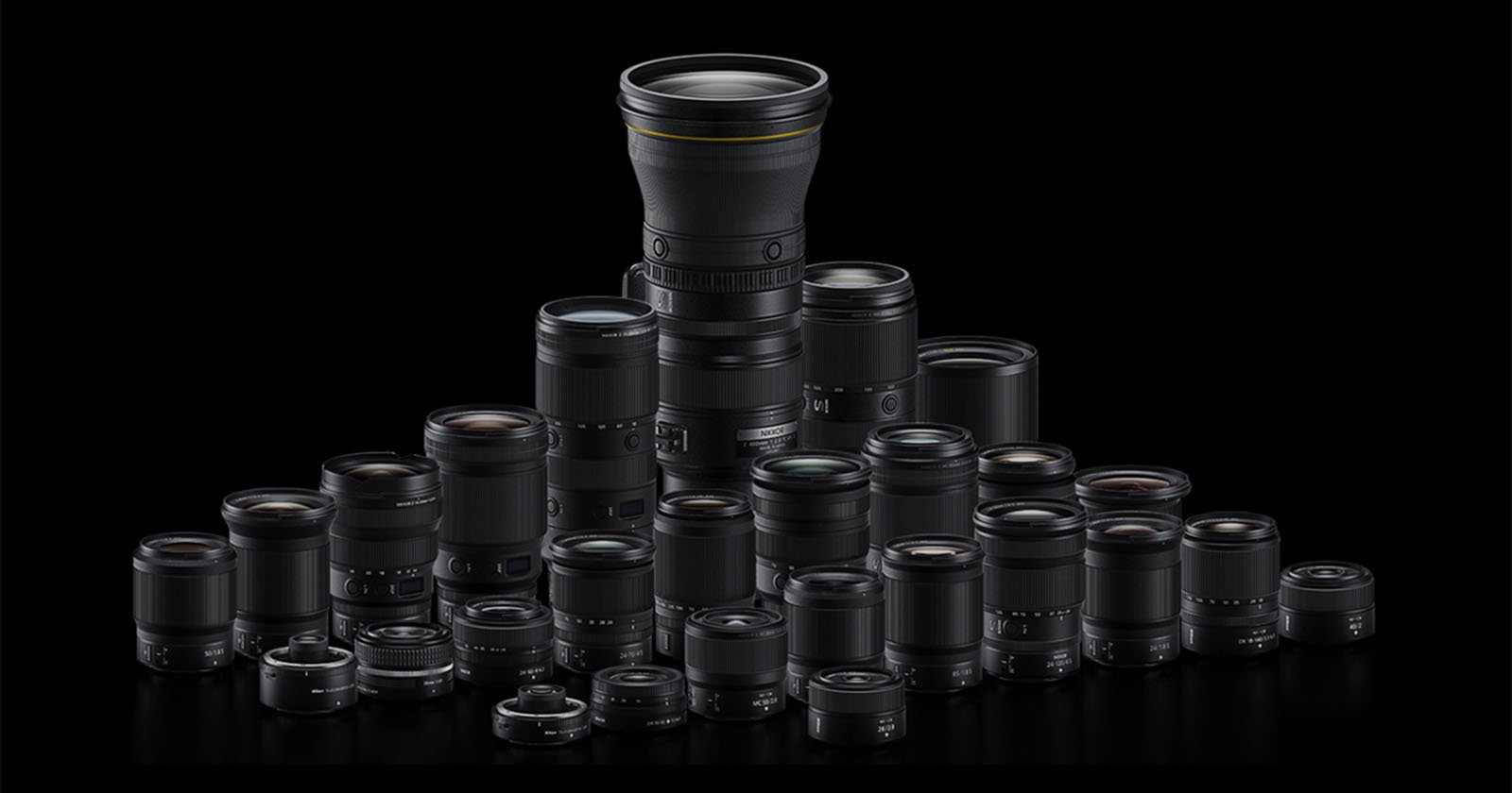 A group of various camera lenses arranged in a semi-pyramid shape on a black background, with one tall lens prominently positioned at the center back.
