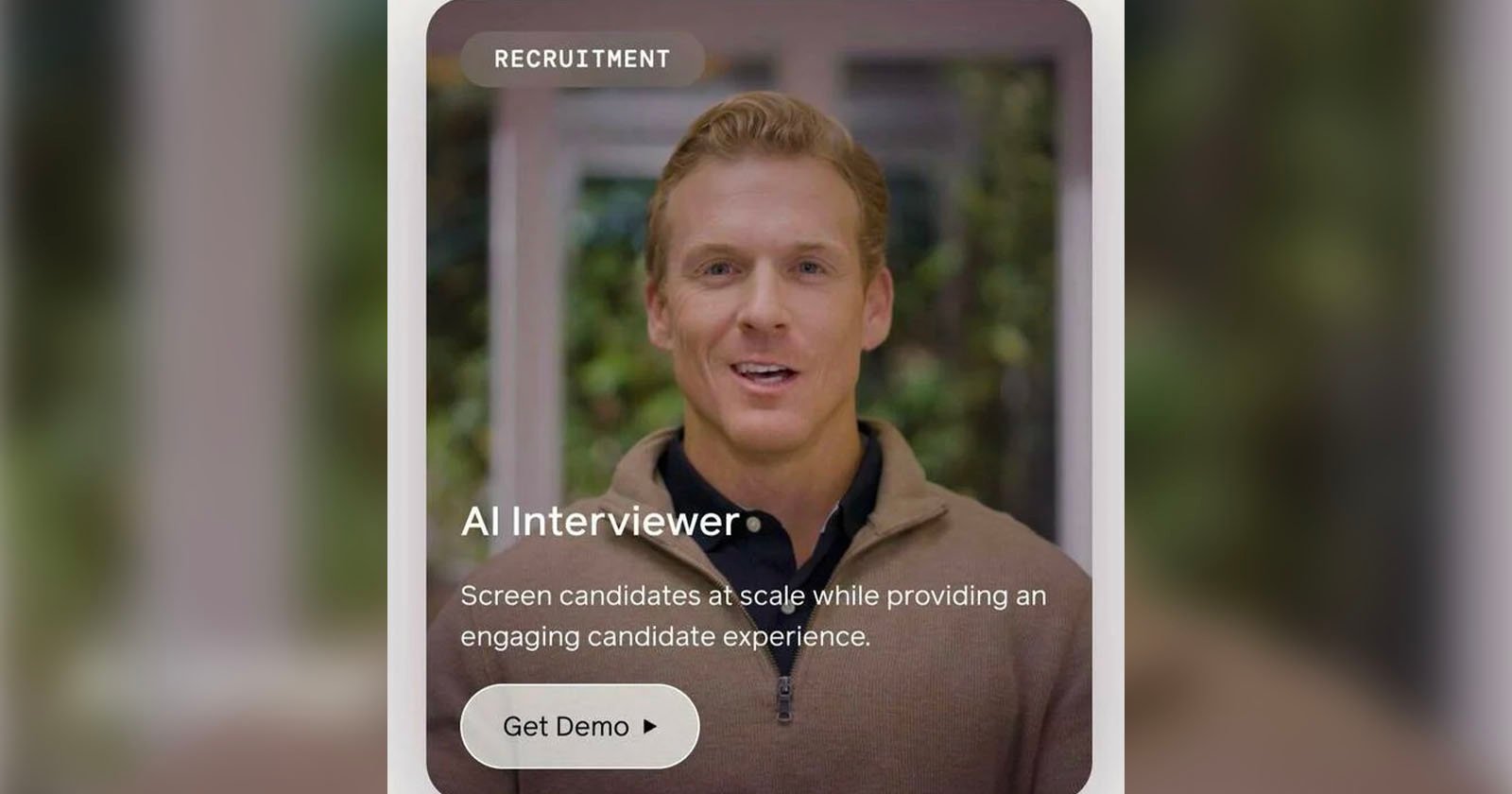 A man with short, light brown hair and a brown sweater speaks in a video. The text reads: RECRUITMENT AI Interviewer Screen candidates at scale while providing an engaging candidate experience. Get Demo. The background is blurred greenery.