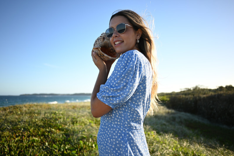 Portrait of a woman with a large sea shell held to her ear