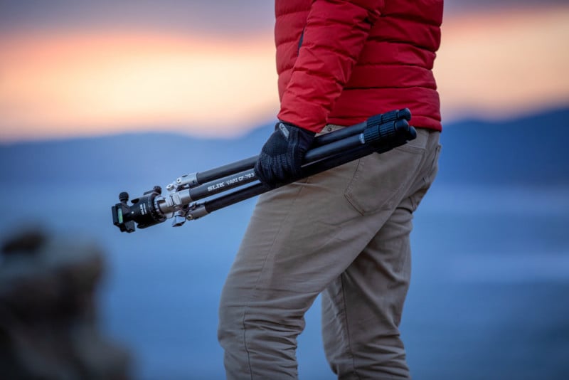 A man in a red jacket holding a tripod