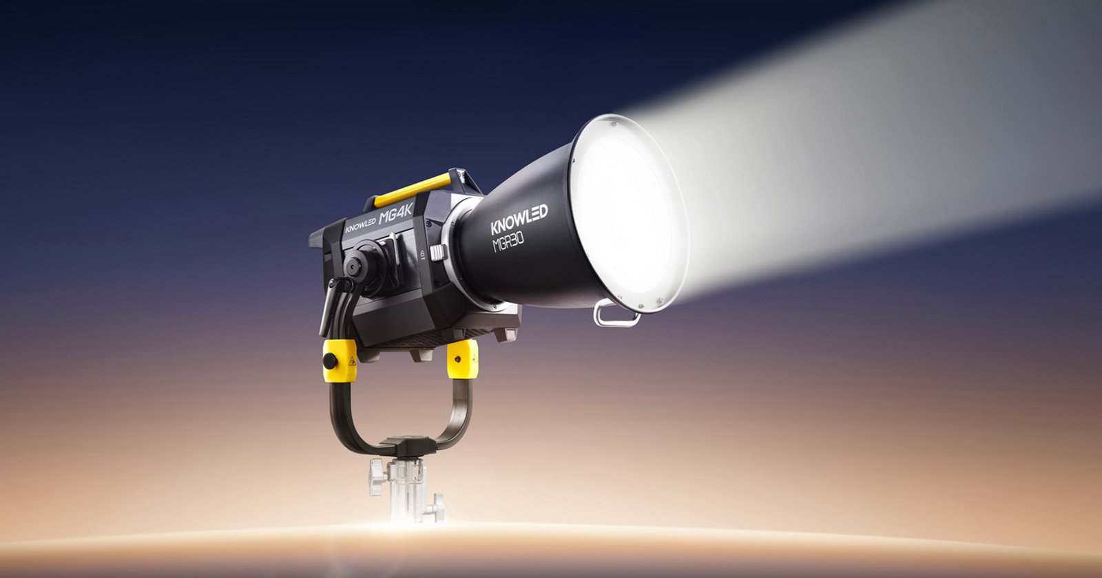 A powerful studio light with the brand name “KNOWLED” emits a bright beam. The light is mounted on a metal stand against a gradient background that fades from dark blue to beige.
