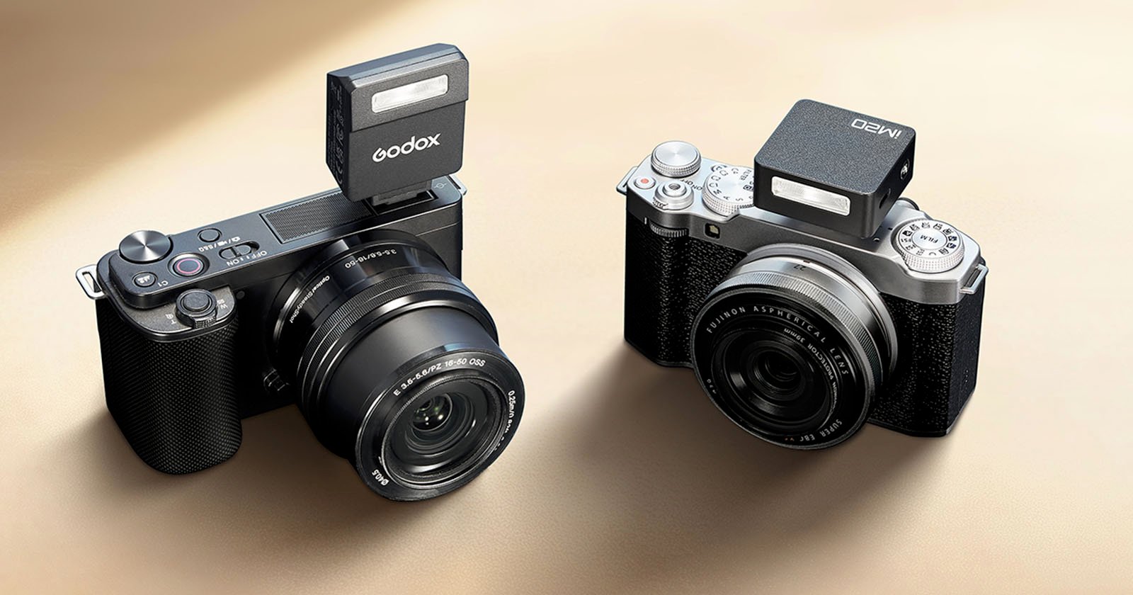 Two digital cameras are displayed, each equipped with a mounted external flash atop. The camera on the left has a Godox flash, while the camera on the right has an AMED flash. Both cameras have a sleek black and silver design.