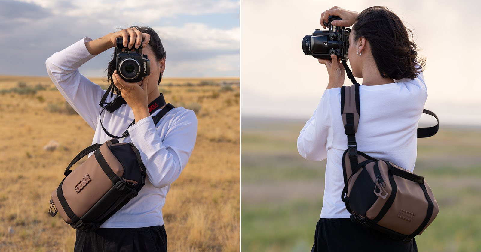 A person wearing a white long-sleeve shirt and black pants stands outdoors in a dry, grassy landscape, holding a camera to their face with a brown crossbody camera bag across their chest.
