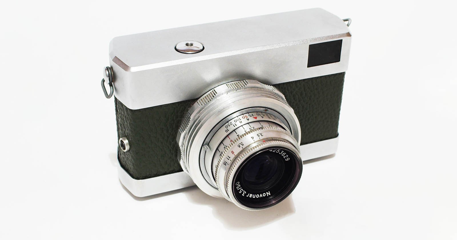 A vintage camera with a silver metal body, textured dark green grip, and a large lens facing forward, displayed on a white background.