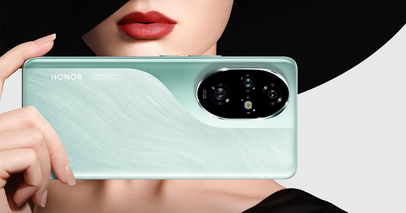 A person with red lipstick and a black hat is holding a mint-green Honor smartphone. The back of the phone features a triple camera setup and the word HONOR is visible. The person’s face is partially obscured.