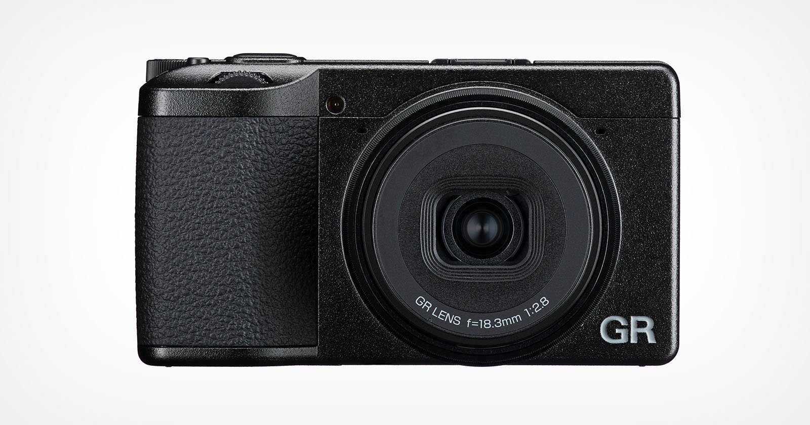 A black compact digital camera with a textured grip, large circular lens labeled GR LENS f=18.3mm 1:2.8, and the letters GR in silver on the bottom right corner of the front.