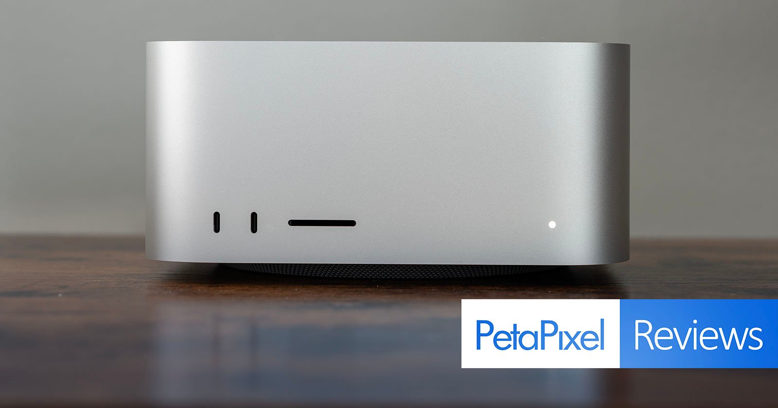 A sleek, silver desktop computer sits on a wooden surface against a plain background. The lower right corner has a PetaPixel Reviews label.