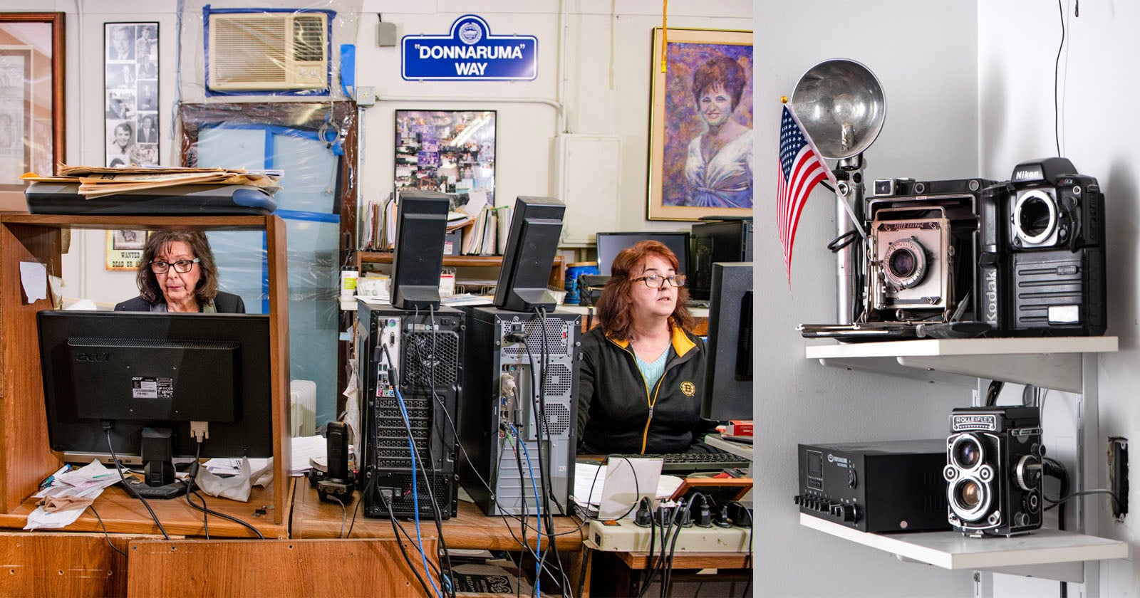 Two women sit at cluttered desks with computers in an office; to the right, shelves display vintage cameras, an old radio, and an American flag. A Donnaruma Way sign hangs on the wall behind them.