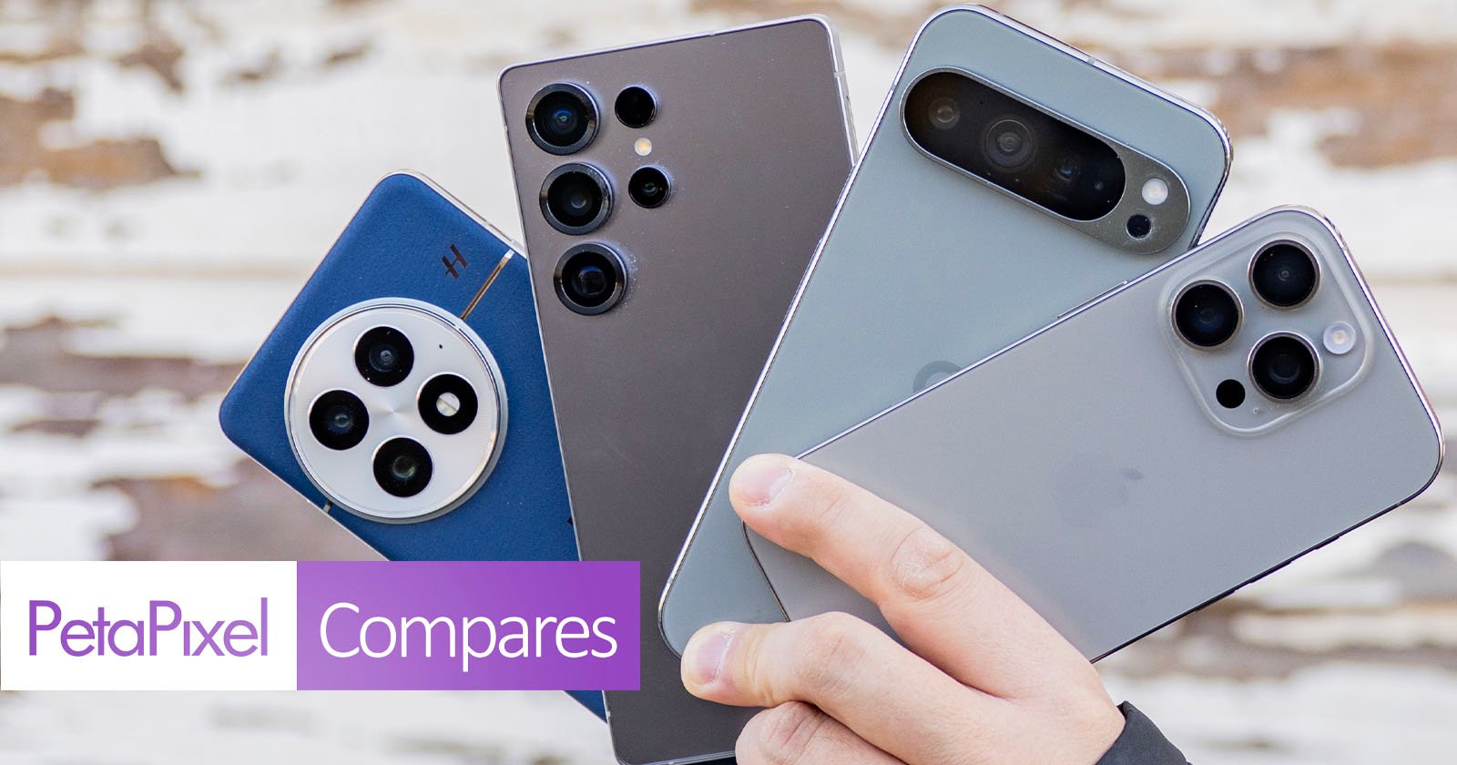 A hand holds four smartphones with multiple camera lenses on their backs. The devices vary in color and design. The background features a blurred, textured surface. The bottom left includes the text PetaPixel Compares.