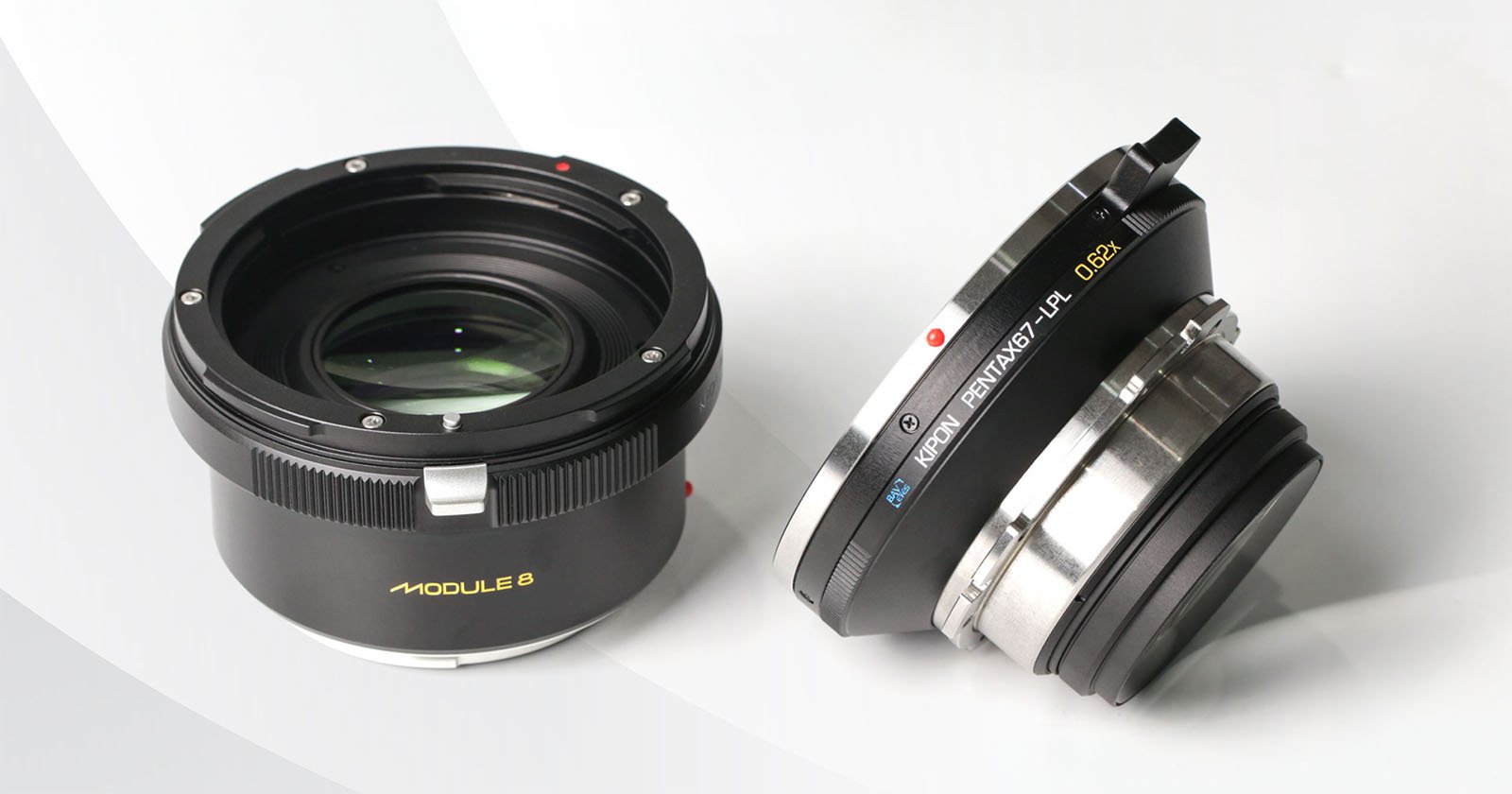 Two camera lenses are pictured against a light background. One lens lies flat showing the glass element, while the other is tilted, displaying the text KERLEE IBERIT 33mm F0.9. The lenses have a sleek black and silver design.