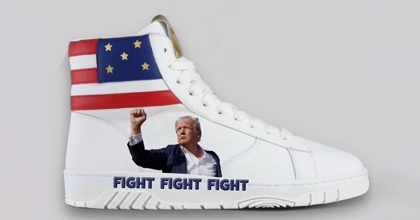 A white high-top sneaker featuring an image of a man in a suit raising his fist. The top section of the shoe shows a stylized American flag with stars. The words FIGHT FIGHT FIGHT are printed near the sole. The background is plain gray.