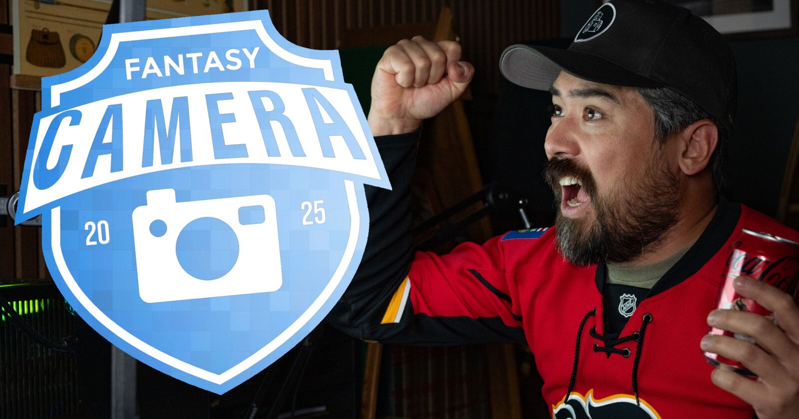 A man in a red hockey jersey and black cap cheers excitedly while holding a can of Coca-Cola. A blue Fantasy Camera 2025 logo with a camera icon is overlaid on the left side of the image.
