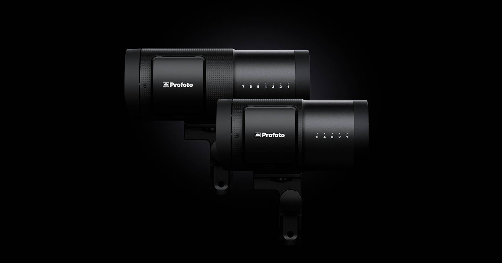 Two black Profoto studio lights are positioned side by side against a dark background, showcasing their sleek, cylindrical design and control panels.