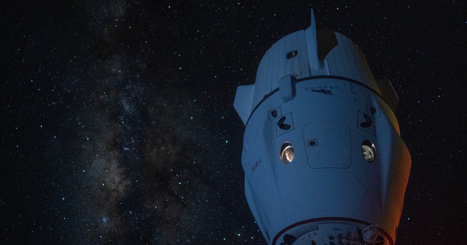 A spacecraft floats in the vast darkness of space with a backdrop of countless stars and the Milky Way galaxy clearly visible. The spacecraft, partly illuminated, showcases its distinctive structure amidst the celestial expanse.