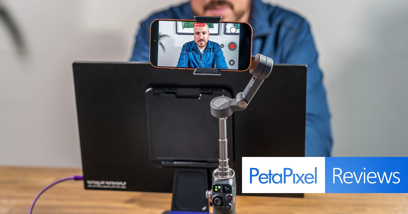 A person sits at a desk with a smartphone mounted on a gimbal, recording a video call. A monitor and the Petapixel Reviews logo are visible in the foreground.