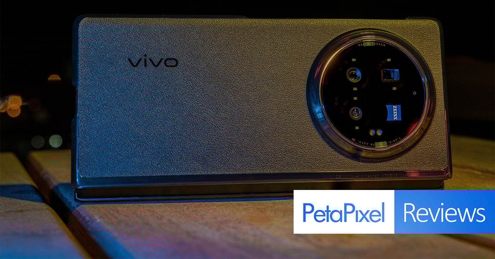 A close-up shot of a Vivo smartphone placed on a table, highlighting its back camera module at night. The text PetaPixel Reviews appears at the bottom right corner of the image.
