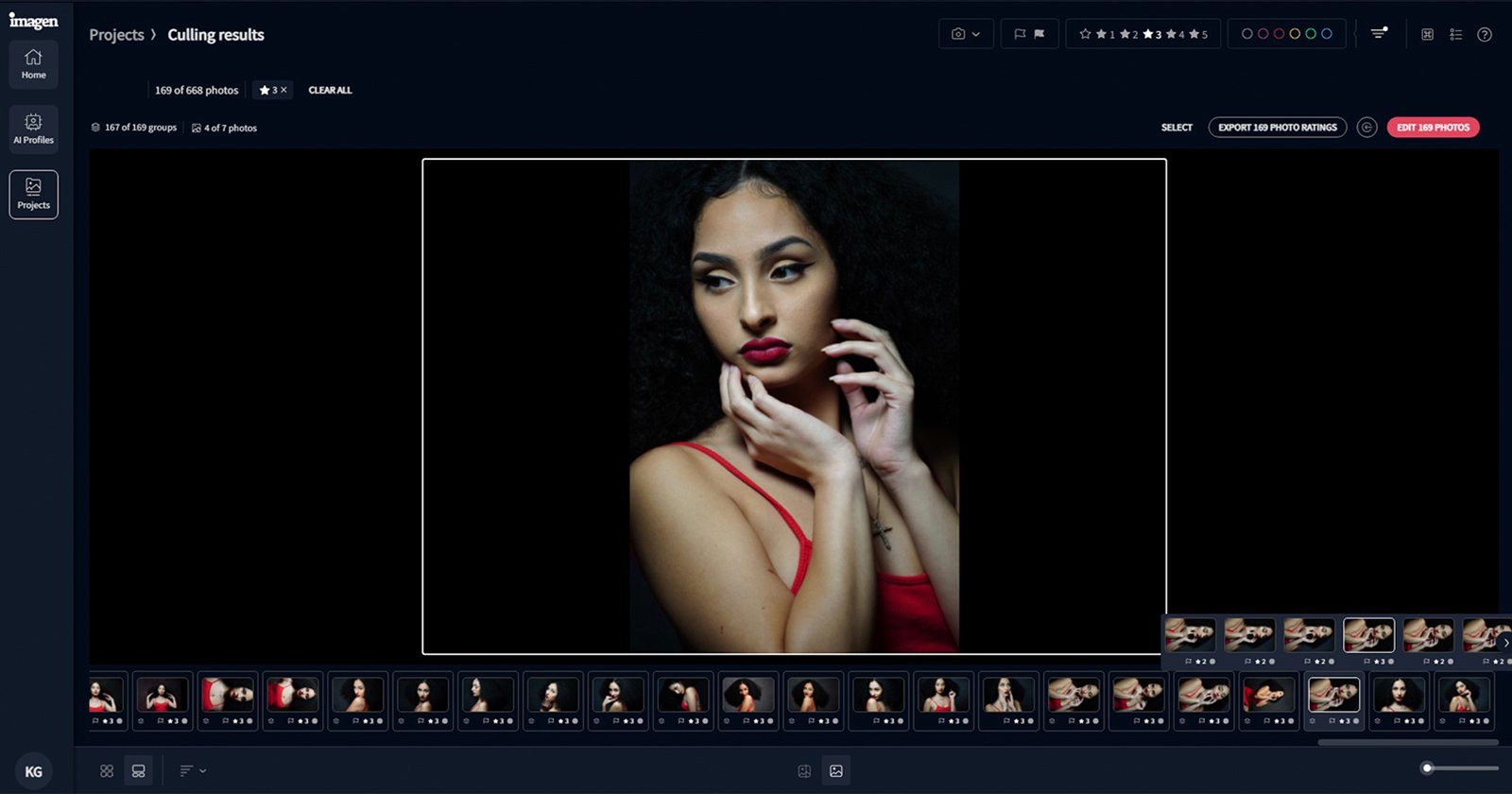 A woman with long, curly hair poses dramatically. She wears a red strappy top and has red lipstick. Her hands are gently framing her face. The background is dark, emphasizing her features.