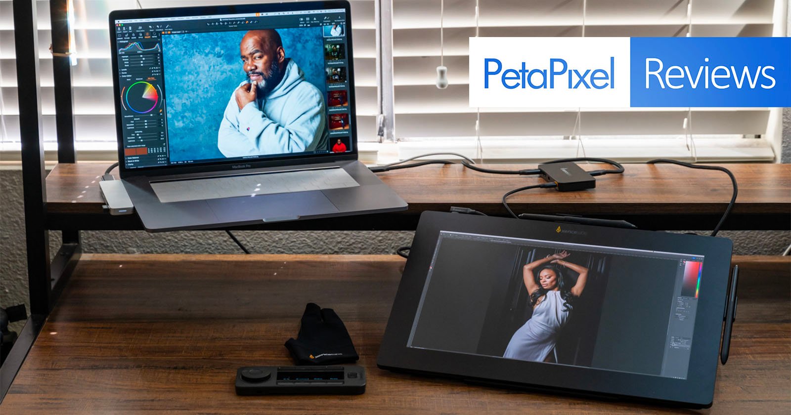 A laptop and a tablet displaying photo editing software are placed on a wooden desk. A man’s portrait is on the laptop screen, while a woman’s portrait is on the tablet screen. Above, the text reads PetaPixel Reviews. A pair of editing gloves and a control deck are on the desk.