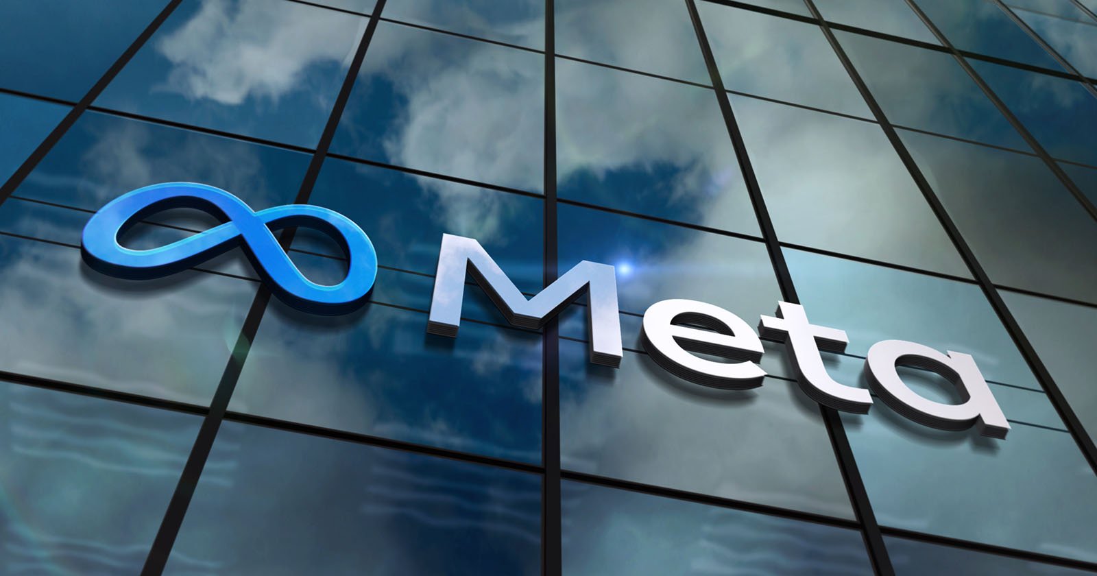 The image shows a building with reflective glass windows, featuring a blue logo resembling an infinity symbol next to the word Meta in white letters. The sky and clouds are mirrored on the building's surface.