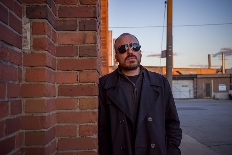 Environmental portrait of a man next to a brick building