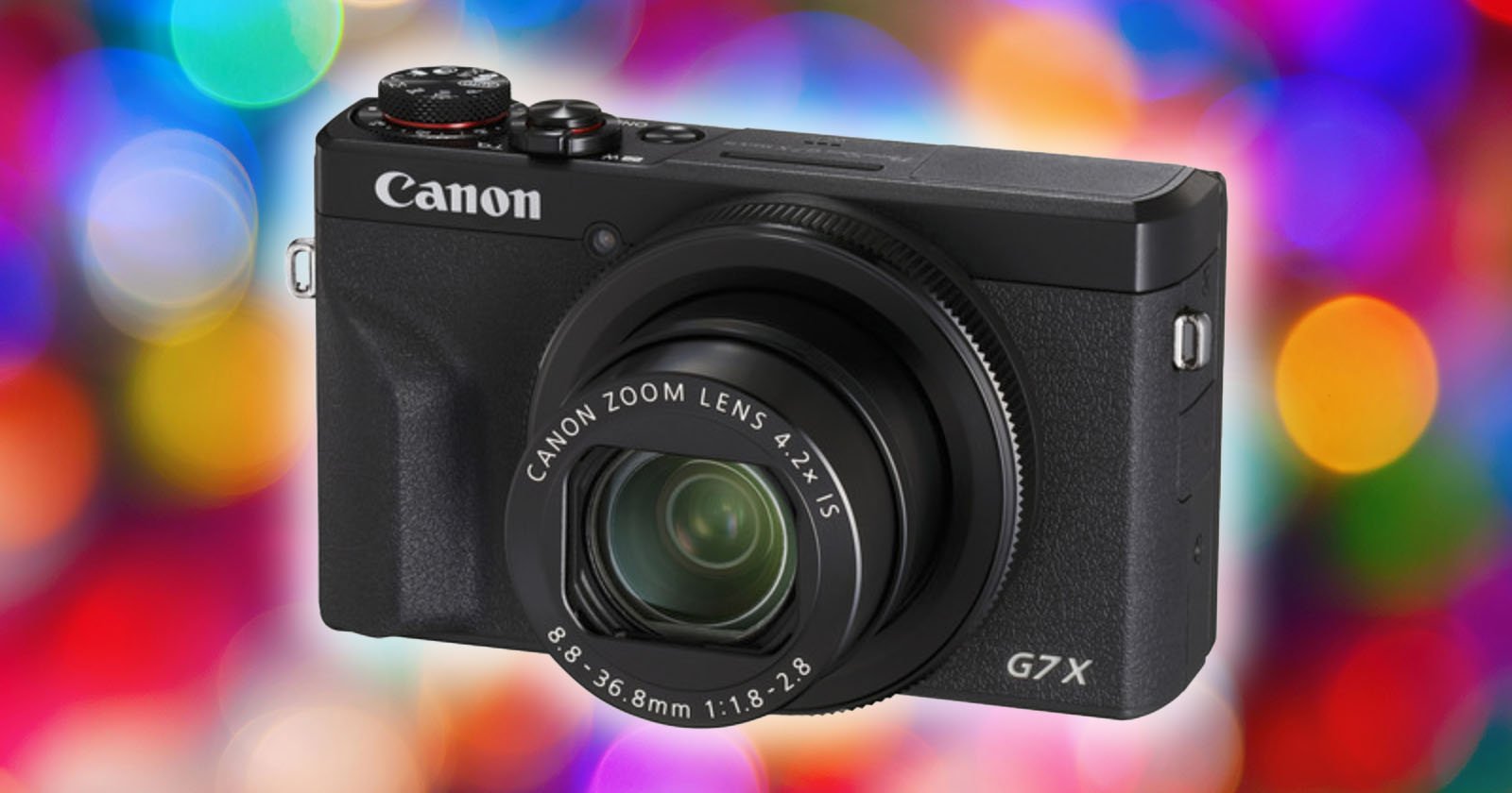 A black Canon G7X camera is centered against a colorful bokeh background. The camera has a protruding lens with text indicating Canon Zoom Lens 4.2x IS. Multicolored circles of light are scattered in the out-of-focus backdrop.
