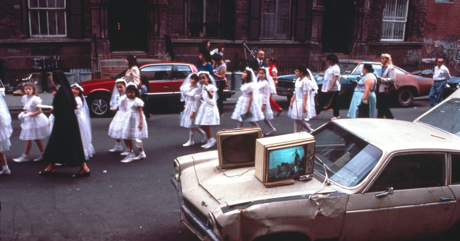 A parade of children participating communion walking on the street.
