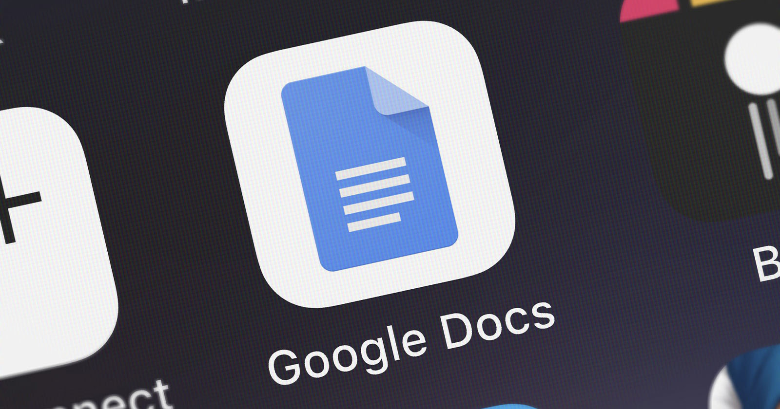 Close-up of the Google Docs app icon on a screen. The icon is blue with a white sheet of paper and three horizontal lines, representing text, in its center. The words Google Docs are visible below the icon.