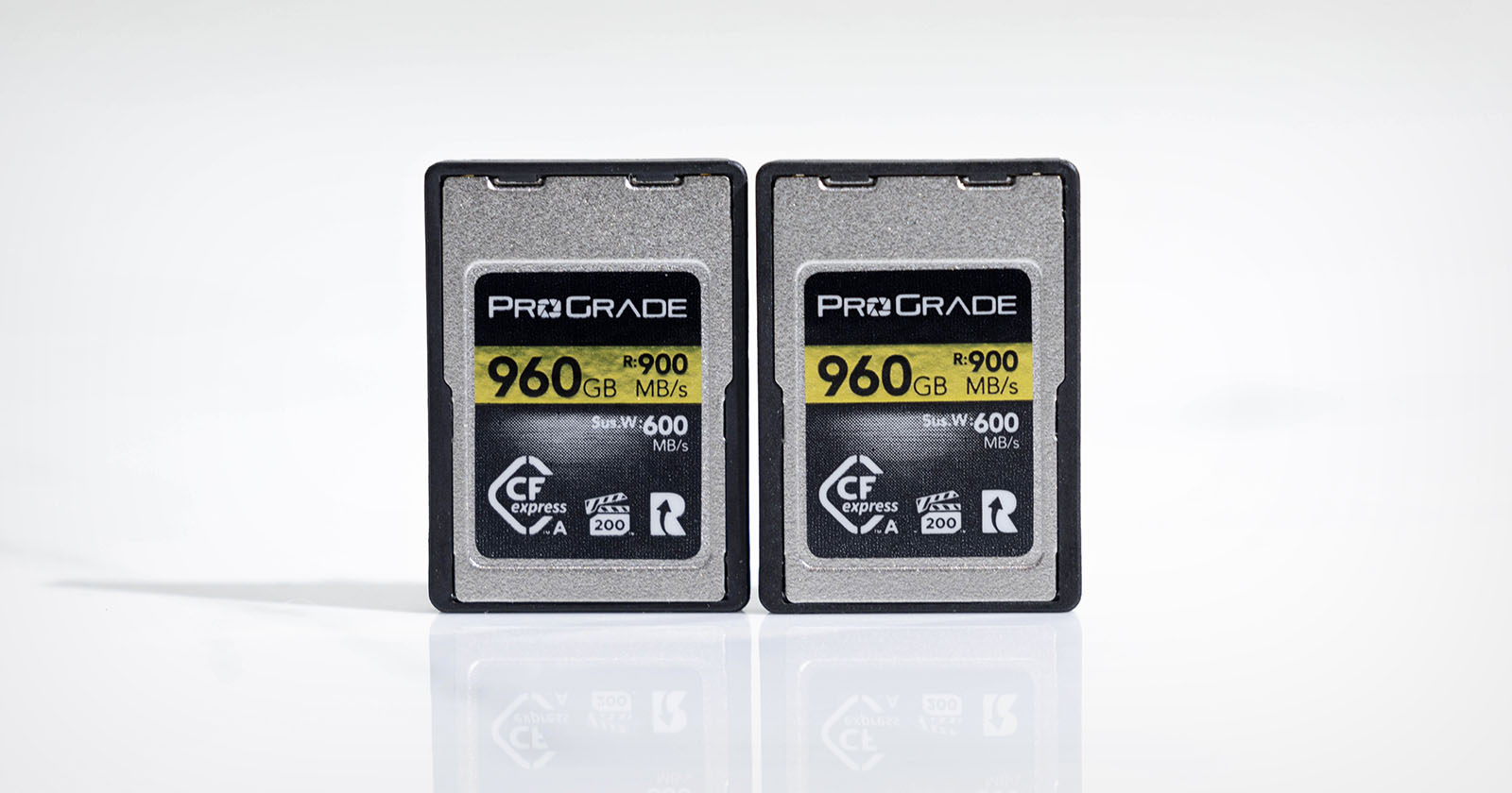 Two ProGrade CFexpress Type A memory cards, each with a capacity of 960GB and speed up to 900 MB/s, are standing upright side by side on a reflective surface. The cards have labels indicating 5K video and VPG 400 support.
