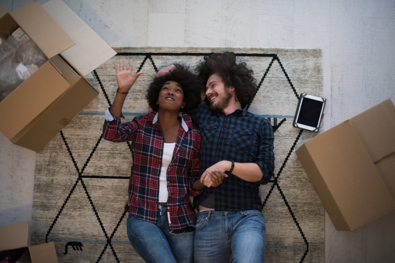 storyblocks-top-view-of-attractive-young-multiethnic-couple-moving-holding-hands-looking-at-camera-and-smiling-while-lying-among-cardboard-boxes_HdH8UQX2--800x534.jpg