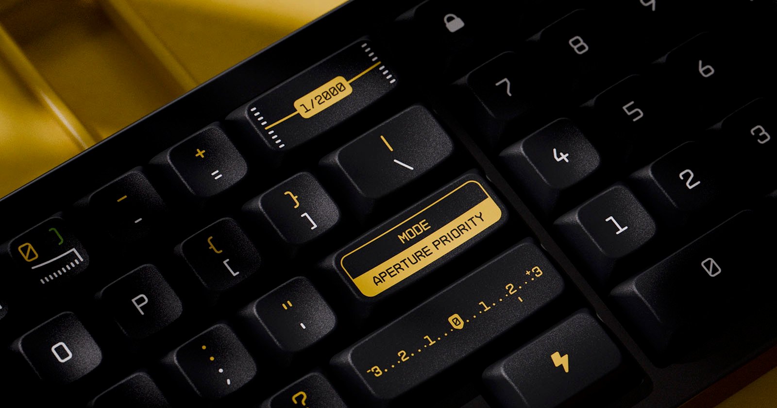 Close-up of a mechanical keyboard with black keys and yellow text. One key reads MODE APERTURE PRIORITY, while others show various icons and numbers, including a camera aperture symbol and a lightning bolt.