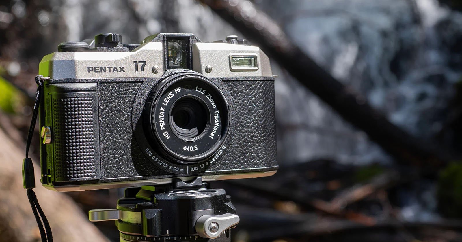 Close-up of a vintage Pentax camera mounted on a tripod. The lens reads ASAHI PENTAX 45mm f/4.5 1:2-3.5 zoom (modular). The background is blurred, showcasing an outdoor, natural setting with flowing water and foliage.