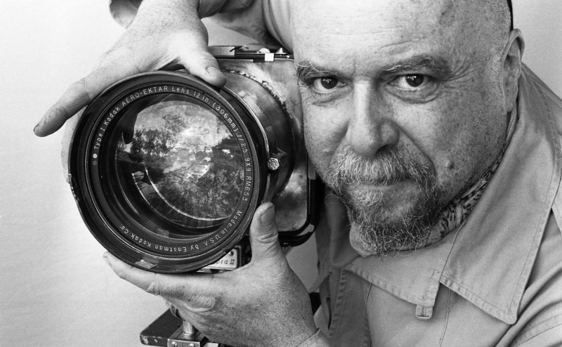 A man with his hands around a camera lens on a large format camera