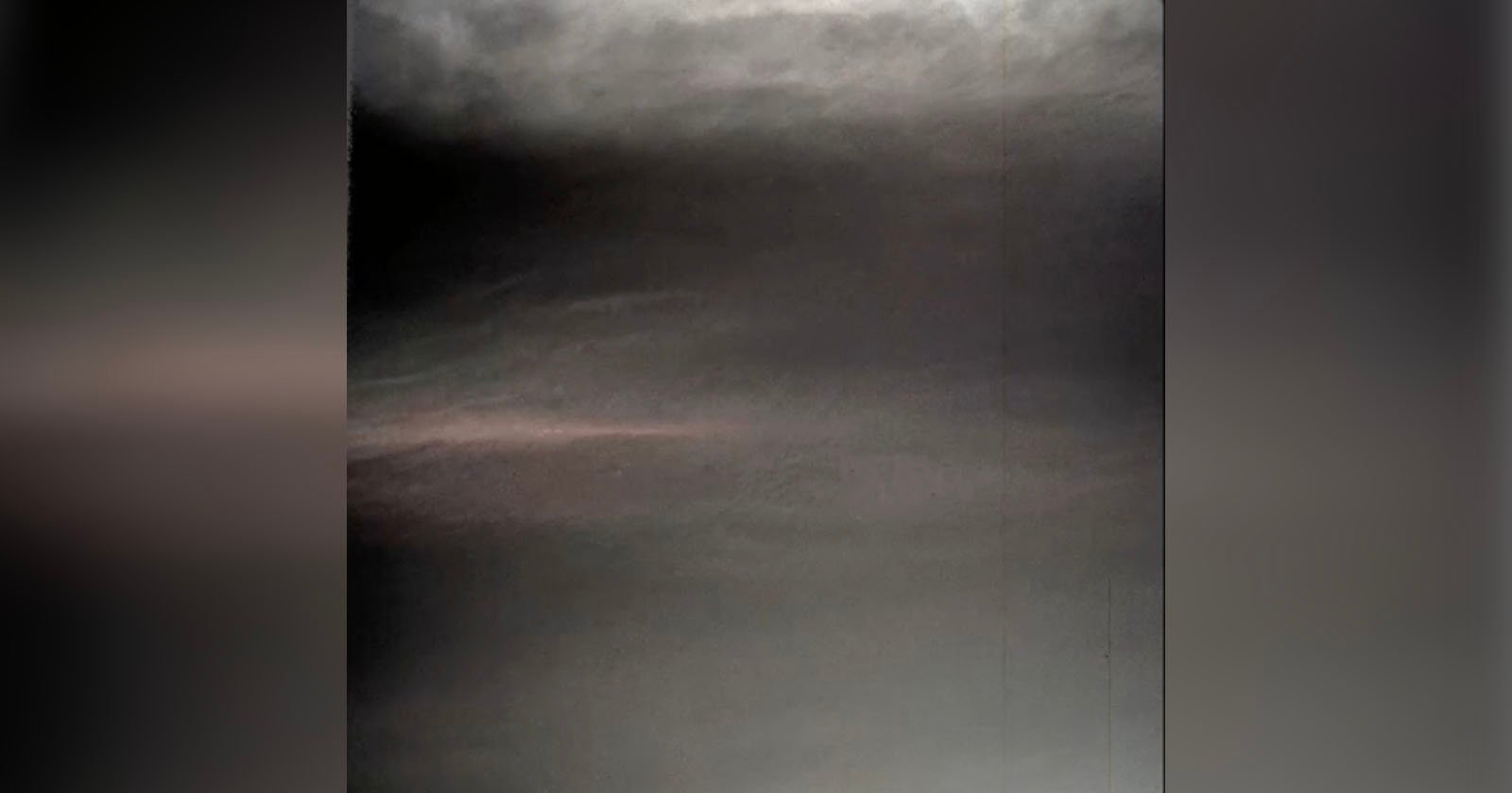 A dark, abstract sky with subtle shades of gray and hints of a pink hue near the horizon, creating a moody and atmospheric effect.