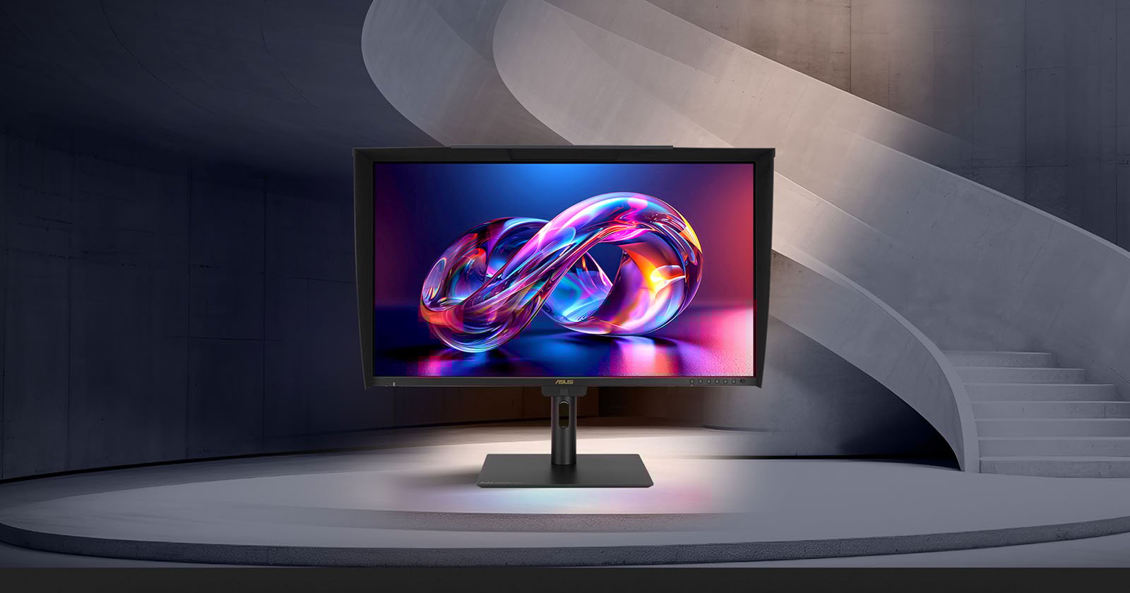 A computer monitor displaying a vibrant, abstract infinity symbol stands on a modern circular platform, with a curved concrete staircase and walls in the background.