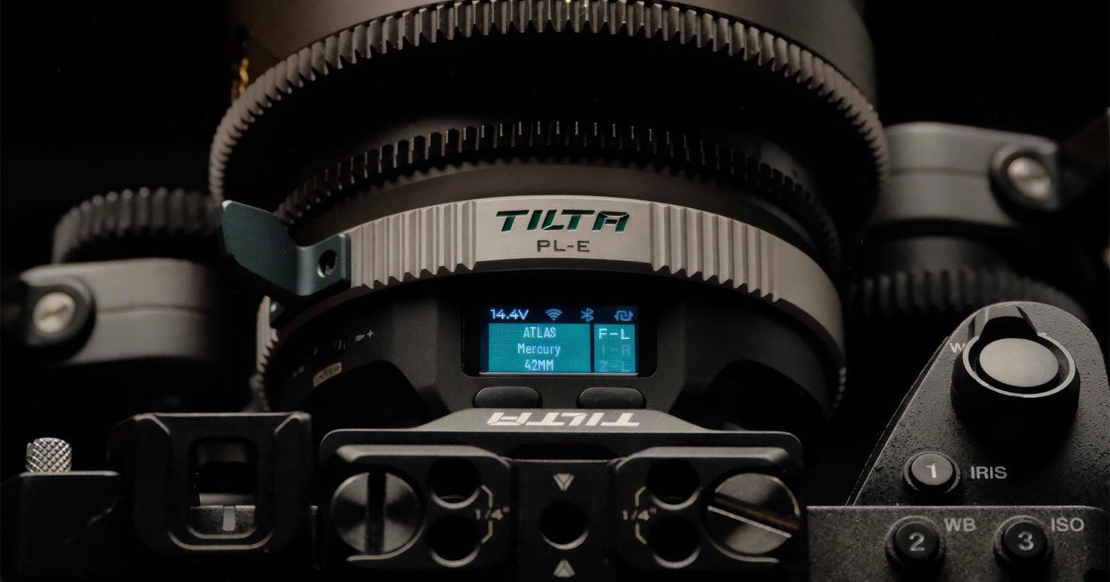 Close-up of a professional camera lens with TILTA PL-E branding, a digital display showing lens settings, and various camera controls in view. The image highlights intricate lens details and equipment.