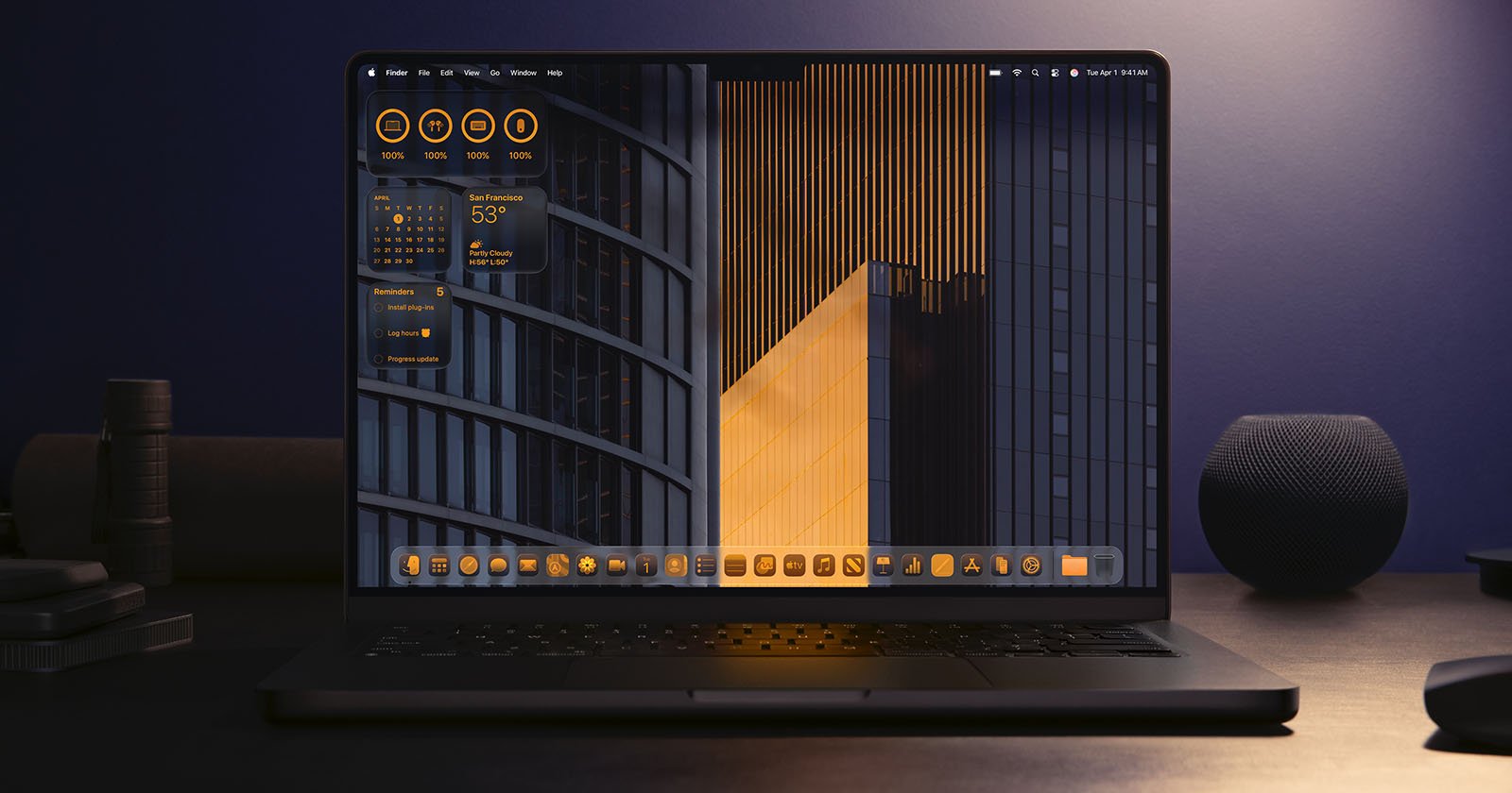 A laptop on a dark desk displays a desktop with orange and black geometric wallpaper, orange-themed icons, and widgets showing system stats and weather. The background includes modern building structures.
