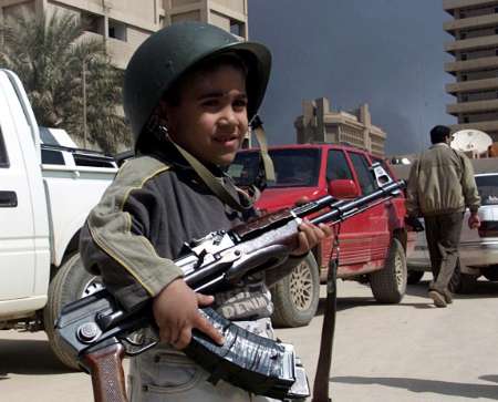 Irakkrieg_-_Iraqi_child_holds_AK-47_rifle_in_front_of_Information_ministery_in_Baghdad_2003-03-29.jpg