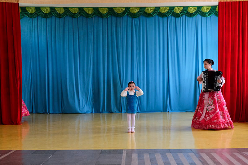 A girl gives a performance accompanied by a teacher (or two) in a junior school in the northeastern port town of Chongjin. Many assume such performances are put on only for the benefit of foreigners. However, Chongjin sees almost no travelers, and such shows are, in fact, a feature at schools throughout the country, where musical talent is identified and pushed from an early age. © Fabian Muir/Courtesy Head On Photo festival