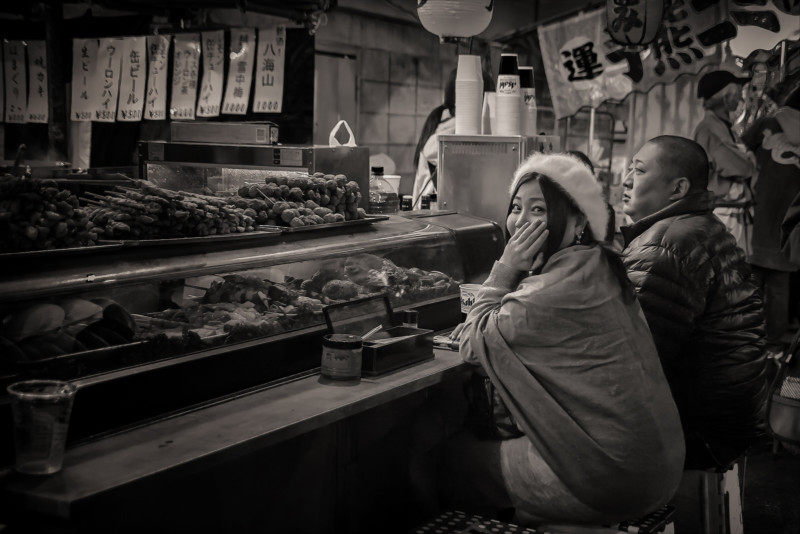 A woman sitting at a counter in a restaurant and looking at the camera