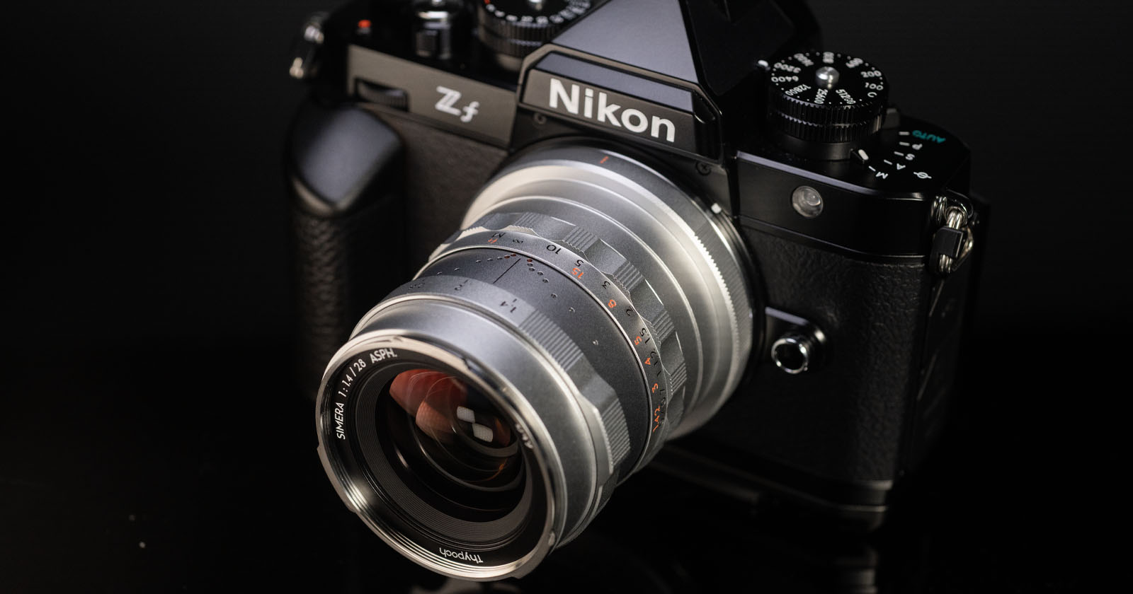 A Nikon Z5 mirrorless camera with a retro-styled silver lens attached, displayed on a reflective black surface, highlighting its detailed design and controls. A Nikon Z5 mirrorless camera with a retro-styled silver lens attached, displayed on a reflective black surface, highlighting its detailed design and controls.