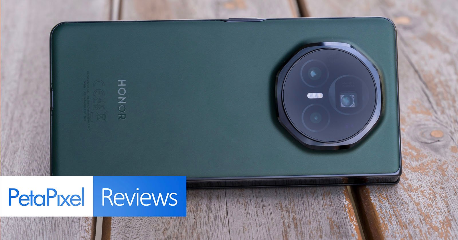 A green Honor smartphone rests on a wooden surface with its camera side facing up. A logo in the bottom left corner reads PetaPixel Reviews. A green Honor smartphone rests on a wooden surface with its camera side facing up. A logo in the bottom left corner reads PetaPixel Reviews.