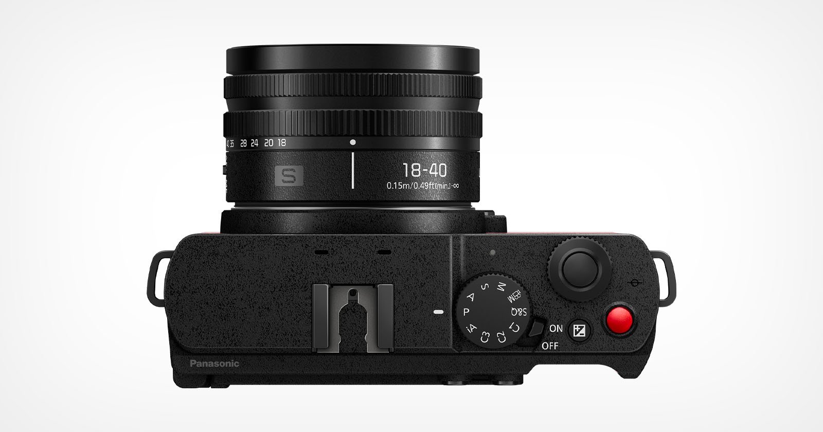 A digital camera viewed from the top, featuring a cylindrical lens with markings 18-40 and 0.5m-0.9ft∞. Controls include a dial, buttons, and a red recording button. The body is black with textured finish, and the Panasonic logo is partially visible. A digital camera viewed from the top, featuring a cylindrical lens with markings 18-40 and 0.5m-0.9ft∞. Controls include a dial, buttons, and a red recording button. The body is black with textured finish, and the Panasonic logo is partially visible.