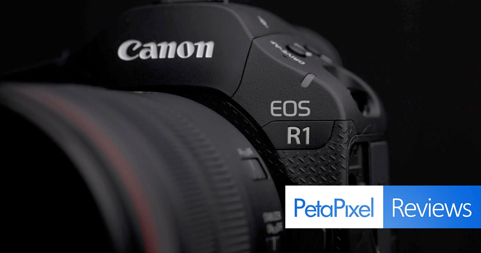 Close-up of a Canon EOS R1 camera showing part of the lens, brand name, and model. Petapixel Reviews logo is partially visible in the lower right corner against a dark background. Close-up of a Canon EOS R1 camera showing part of the lens, brand name, and model. Petapixel Reviews logo is partially visible in the lower right corner against a dark background.